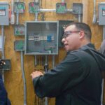 Capstone College student practicing electrical installation with safety equipment